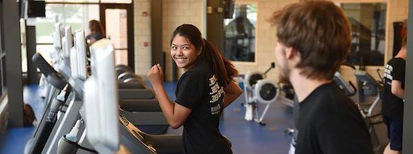 A pair of students are running on treadmills in the Gates Center fitness studio.